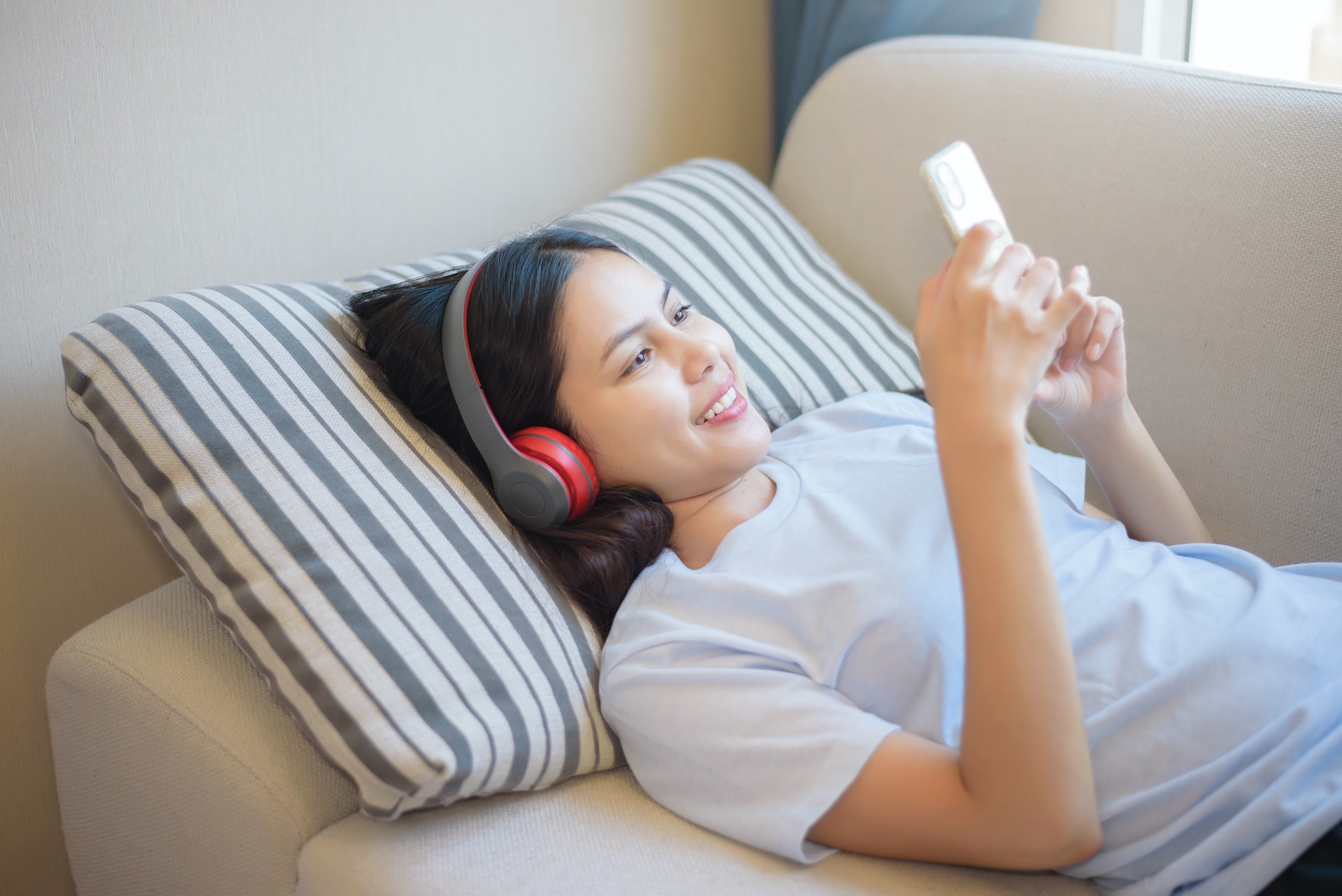 woman listening to audio on headphones while using smartphone